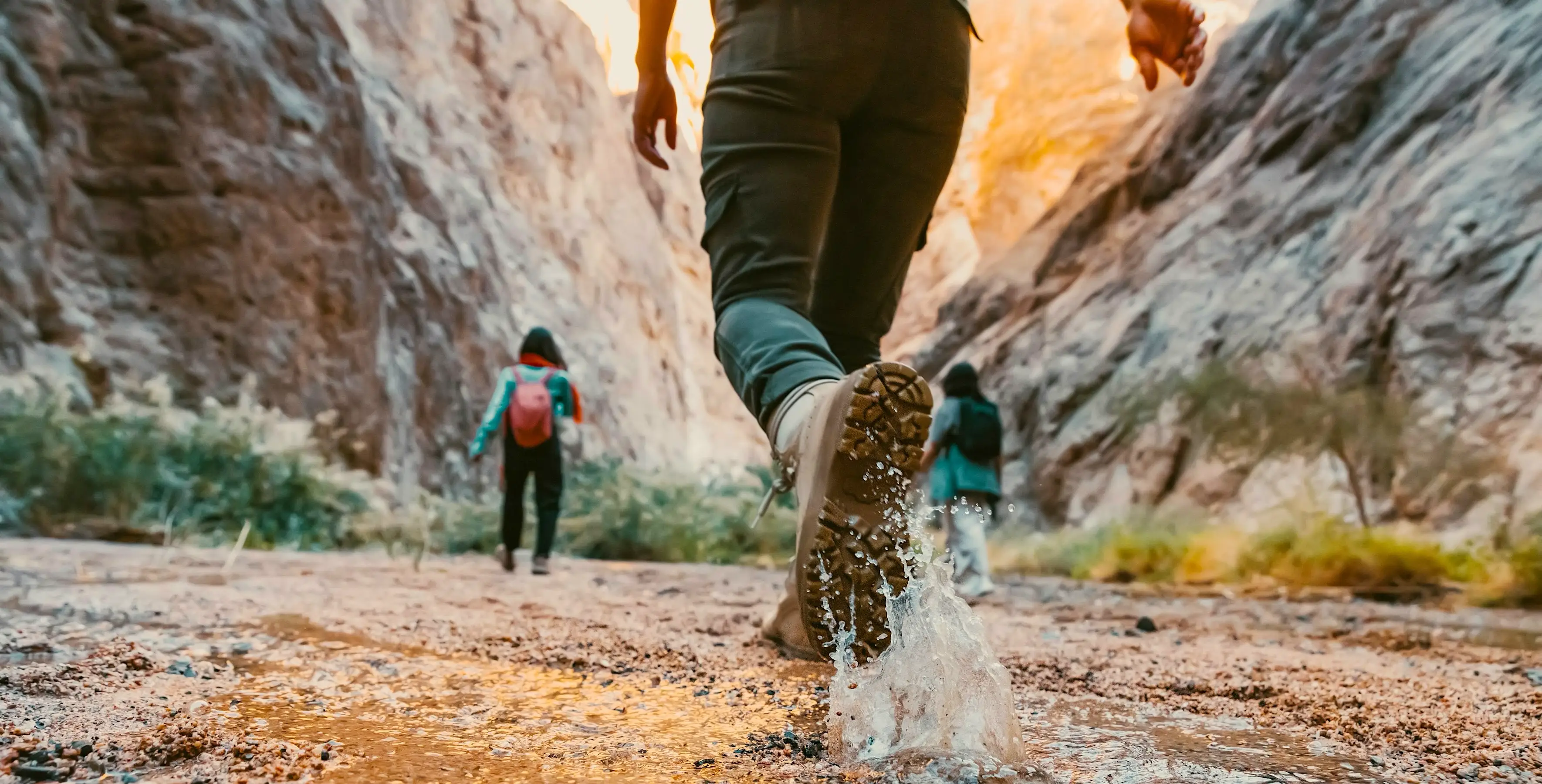 3 hikers hiking in a creek in a canyon